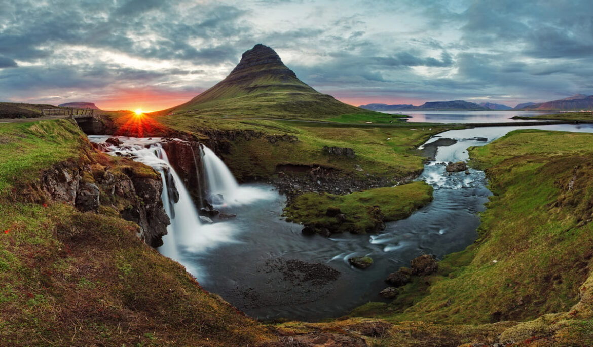 La montagne emblématique Kirkjufell en Islande, entourée de cascades et baignée par la lumière douce du coucher de soleil, formant un paysage naturel spectaculaire et serein.