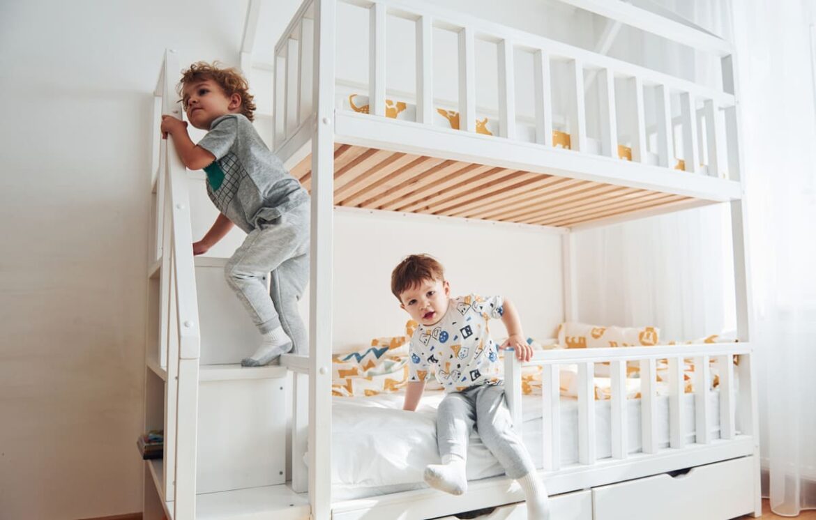Enfants dans une chambre partagée avec lits superposés, décorés de coussins colorés et d'objets personnels.